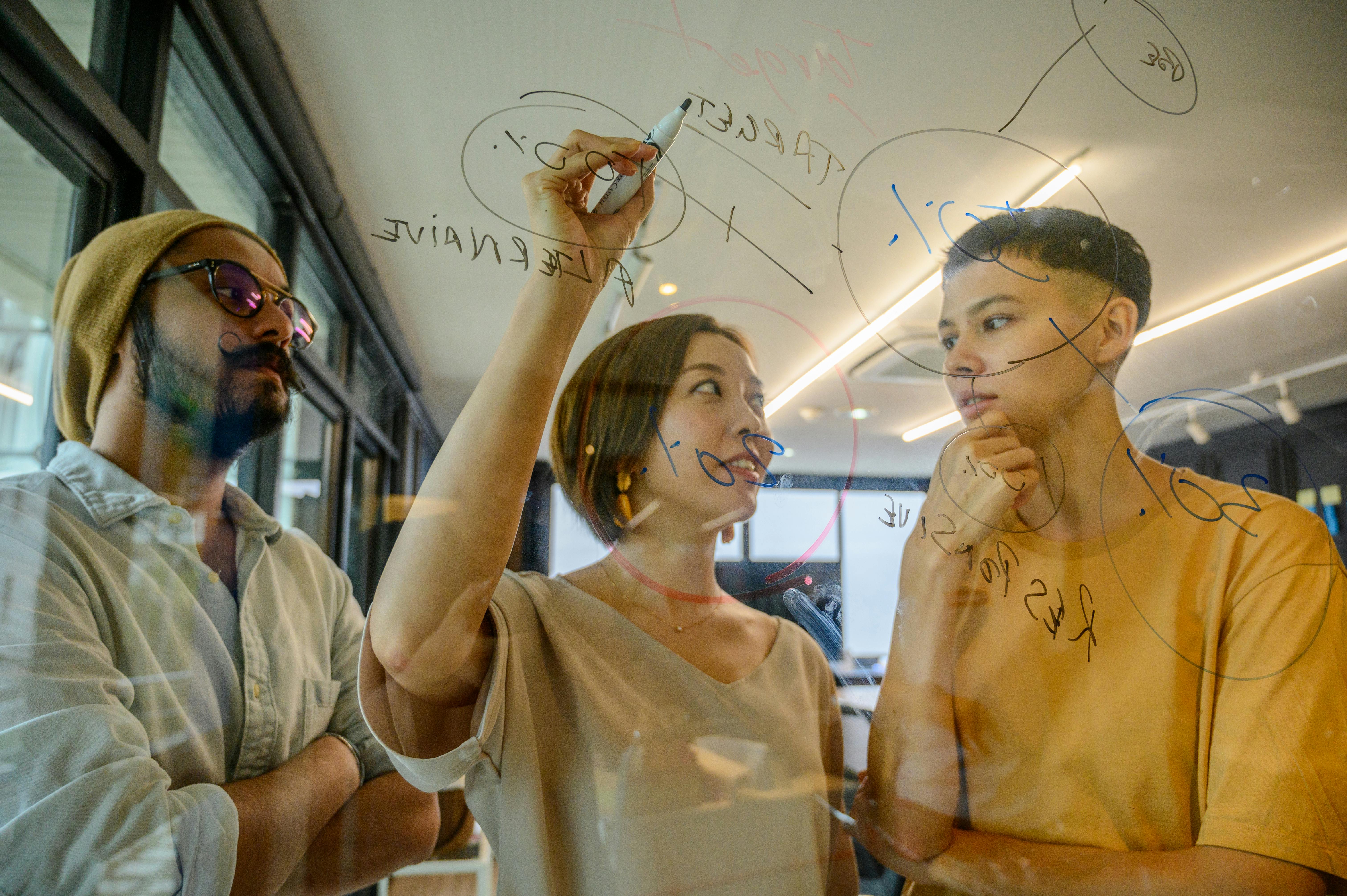 A small group in conversation around a whiteboard.
